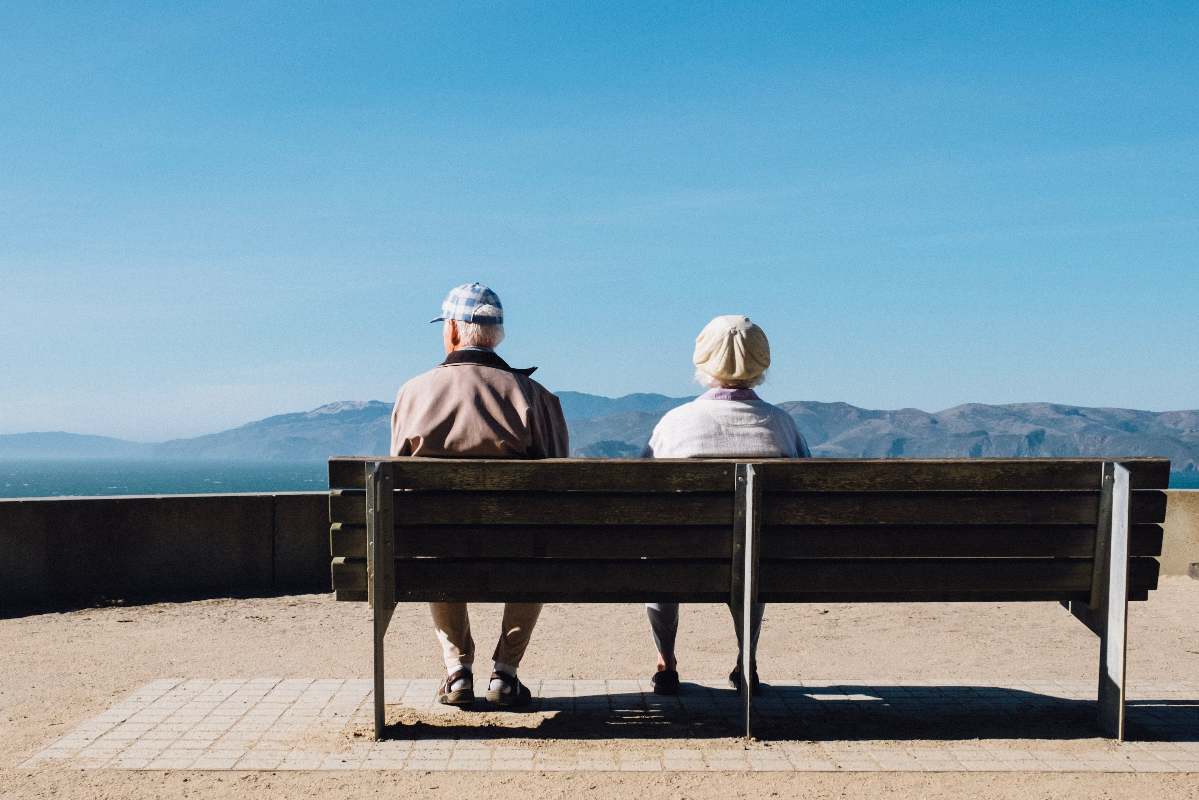 Ein älteres Ehepaar auf einer Parkbank, die von ihrer positiven Erfahrung der BioMetrics®Cura One Gesundheitsuhr berichtet